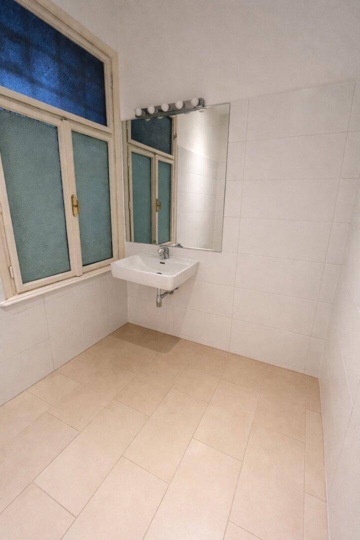 Badezimmer mit Waschbecken, Spiegel und einem Fenster, das für natürliche Belichtung sorgt.