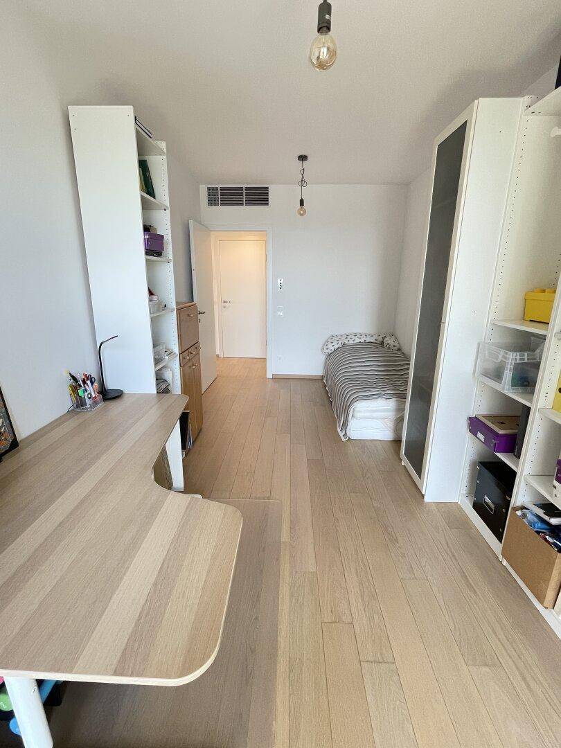 Funktionales Schlafzimmer oder Arbeitszimmer mit Schreibtisch, Bücherregalen und Einzelbett, hell und praktisch.