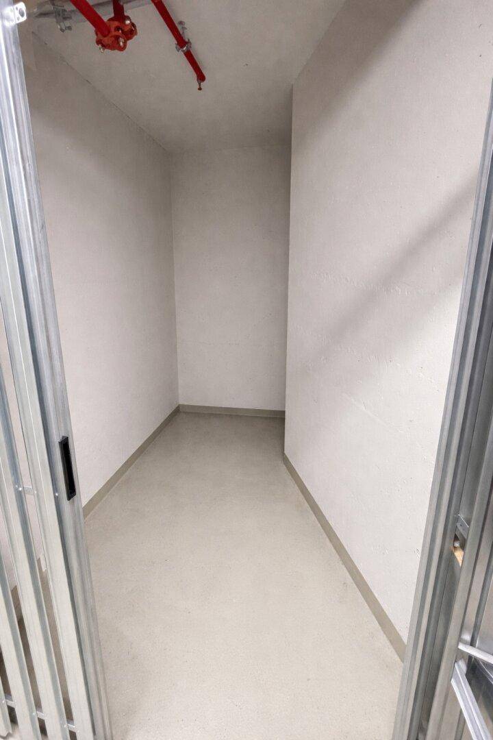 Leerer Abstellraum mit weißen Wänden und hellem Boden, ideal für zusätzlichen Stauraum.