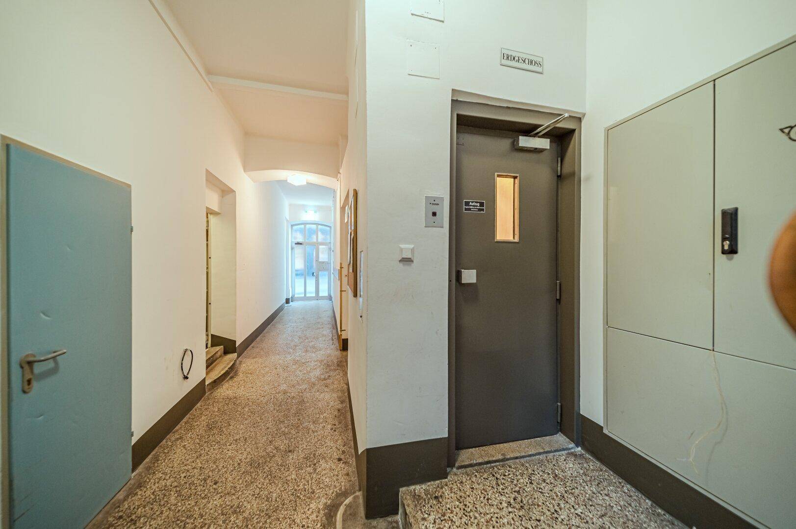 Heller Flur mit Aufzugstür und Zugang zu den Wohnungen in einem Mehrfamilienhaus.