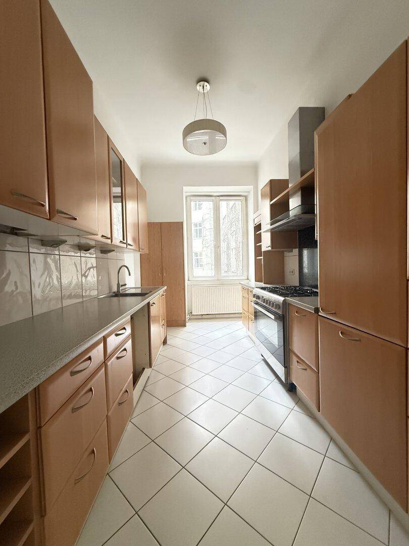 Funktionale Küche mit Holzschränken, Gasherd und Fenster, bereit für den täglichen Gebrauch.