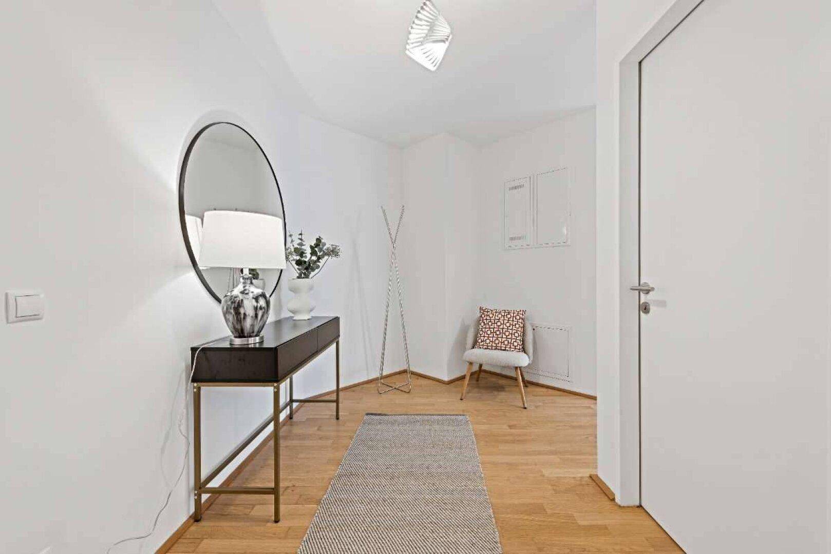 Heller Eingangsbereich mit Holzboden, großem Spiegel und moderner Konsole als Ablagefläche.