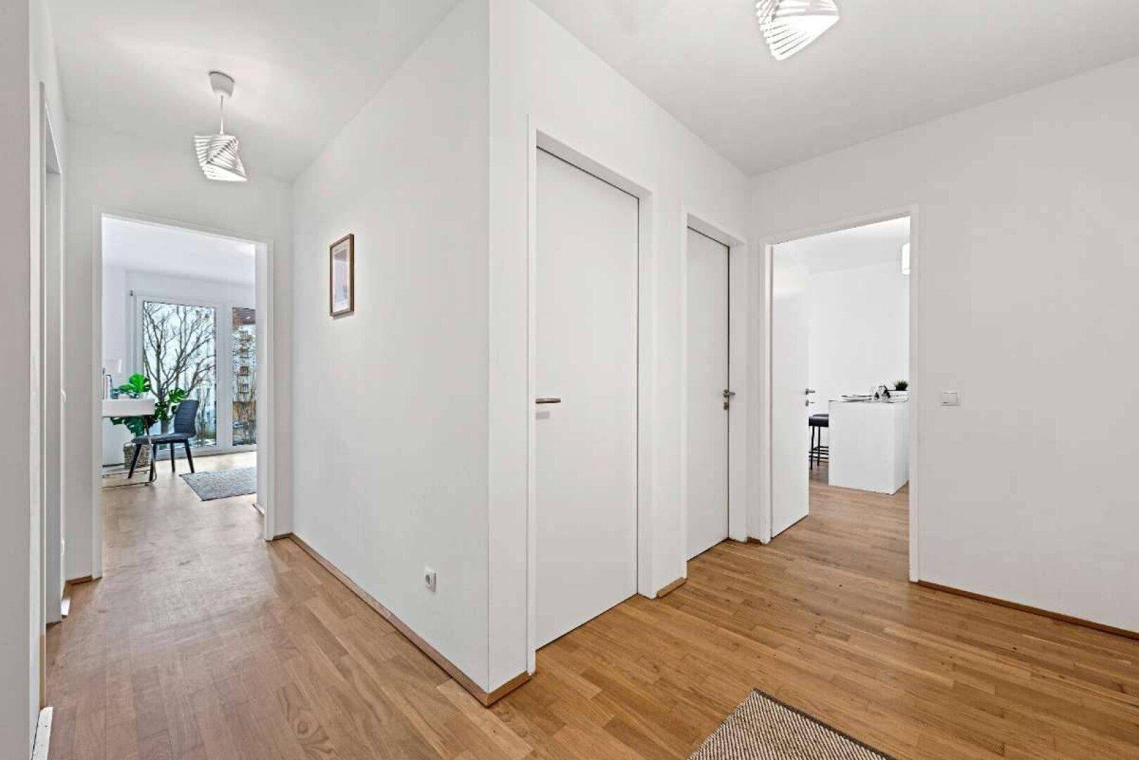 Geräumiger Flur mit Holzboden, weißen Türen und Zugang zu verschiedenen Wohnbereichen.
