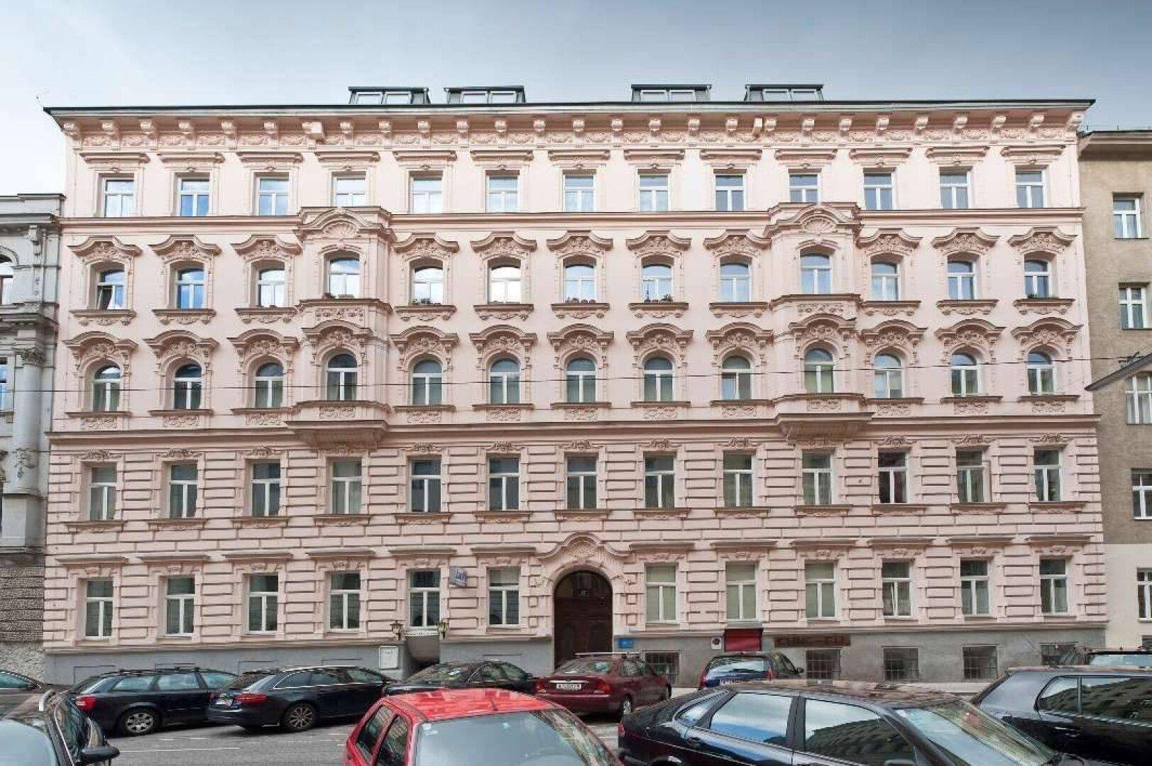 Historisches Wohngebäude mit reich verzierter Fassade und vielen Fenstern in der Stadt.