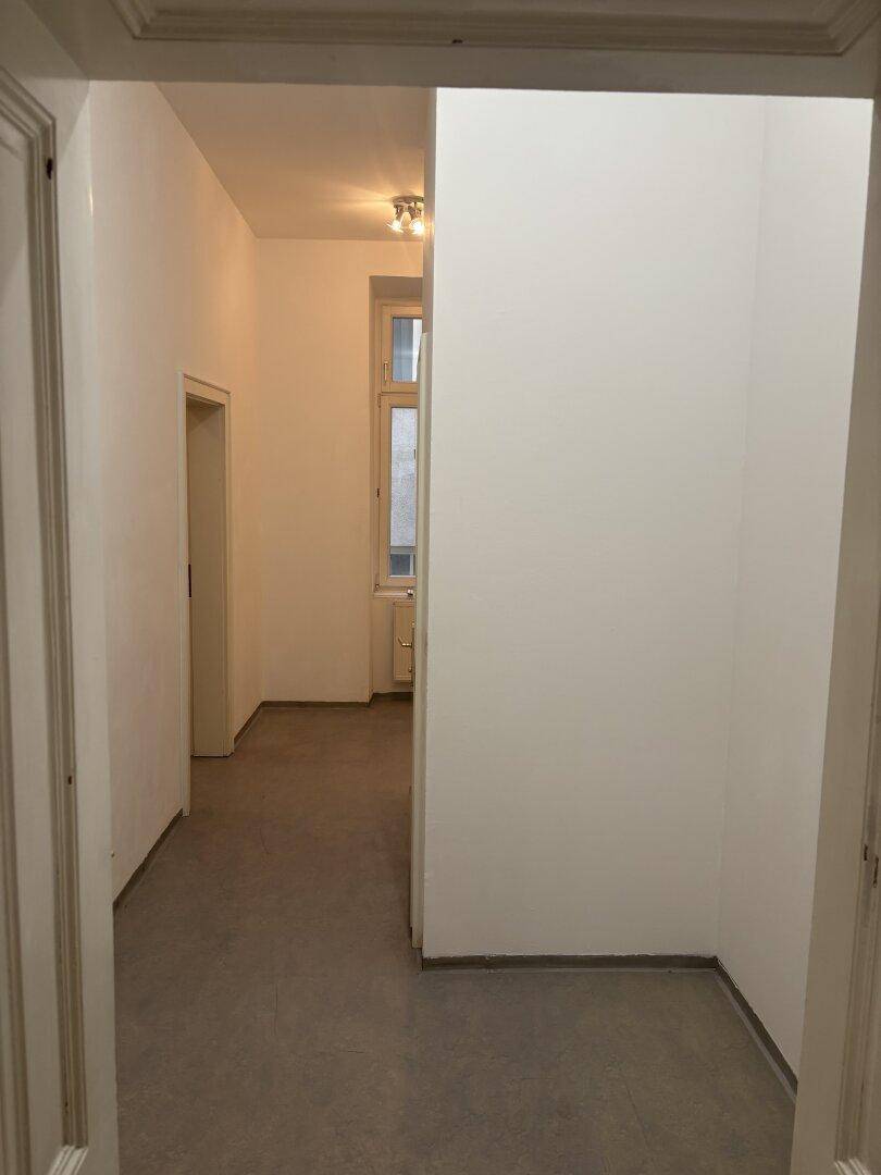 Langer, heller Flur mit Fliesenboden, der zu weiteren Räumen der Wohnung führt.