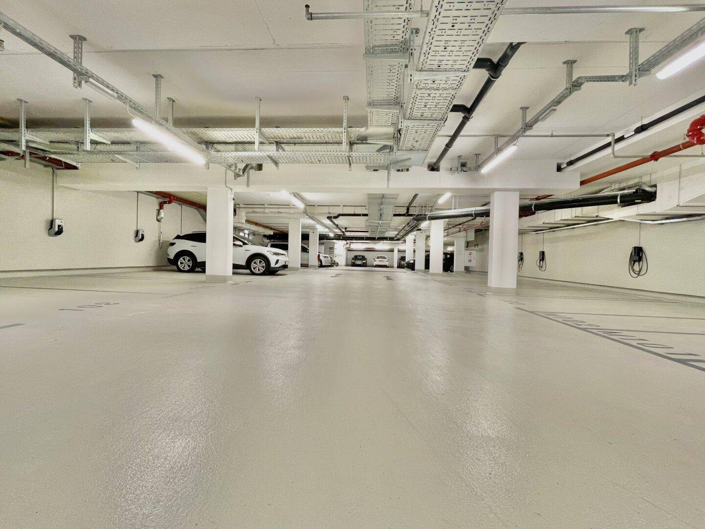 Moderne Tiefgarage mit zahlreichen Stellplätzen und Ladestationen für Elektrofahrzeuge.