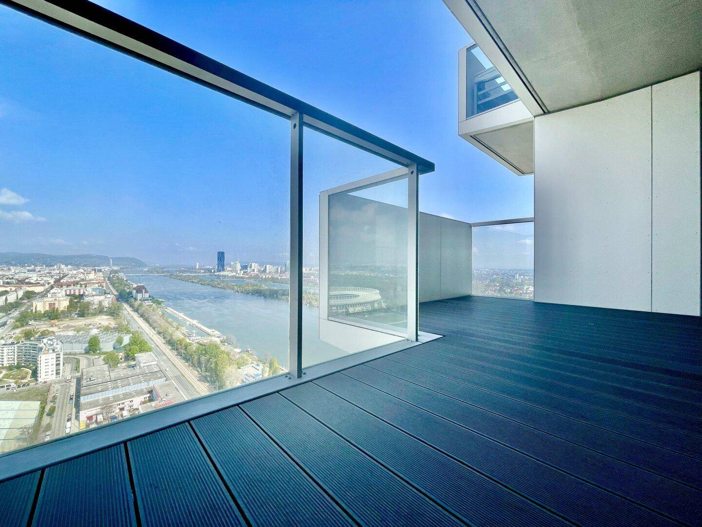 Moderner Balkon mit Glasgeländer und beeindruckendem Blick auf die Donau und die Stadtlandschaft.
