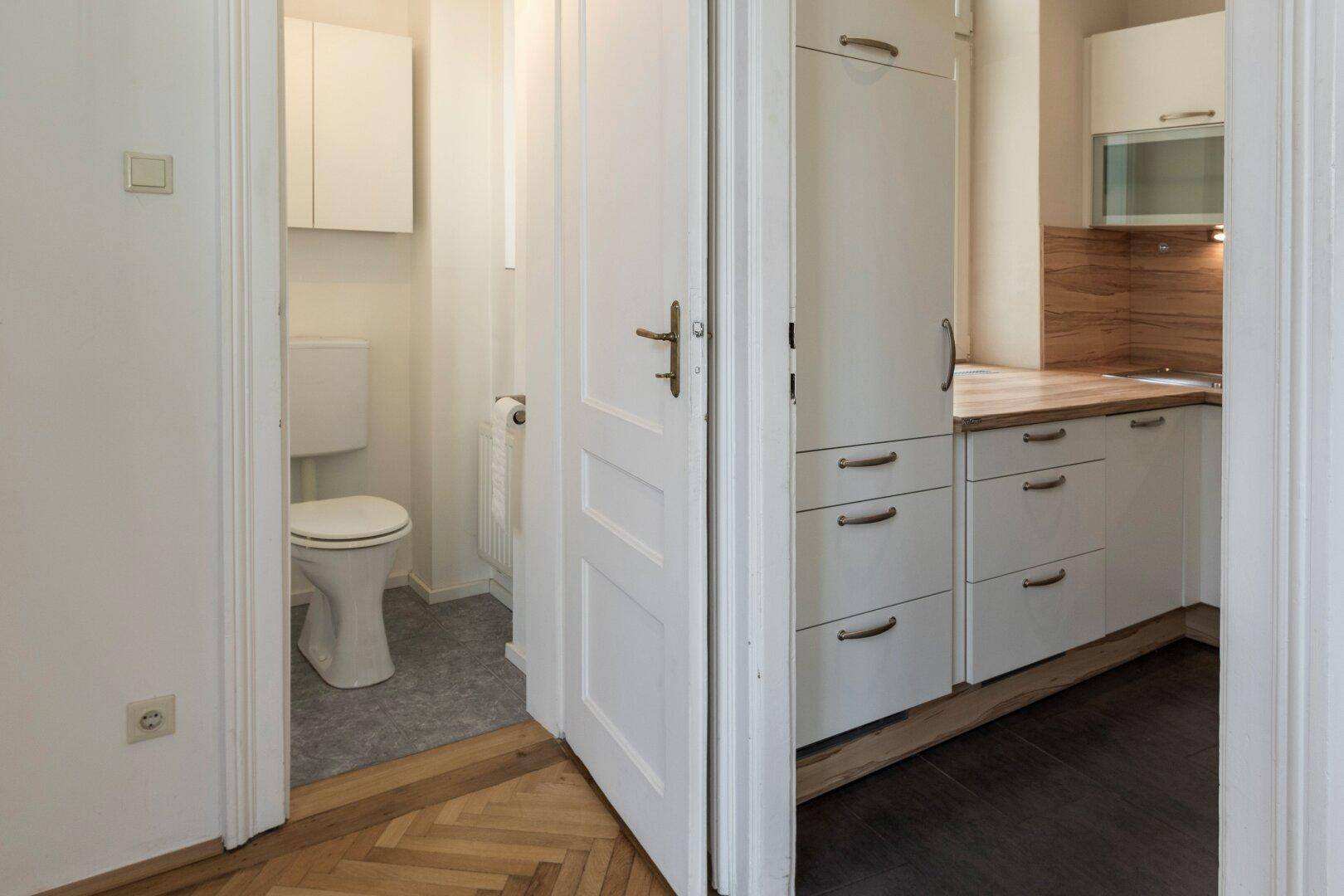 Separates WC mit Toilette und Zugang zu einer modernen Küche.