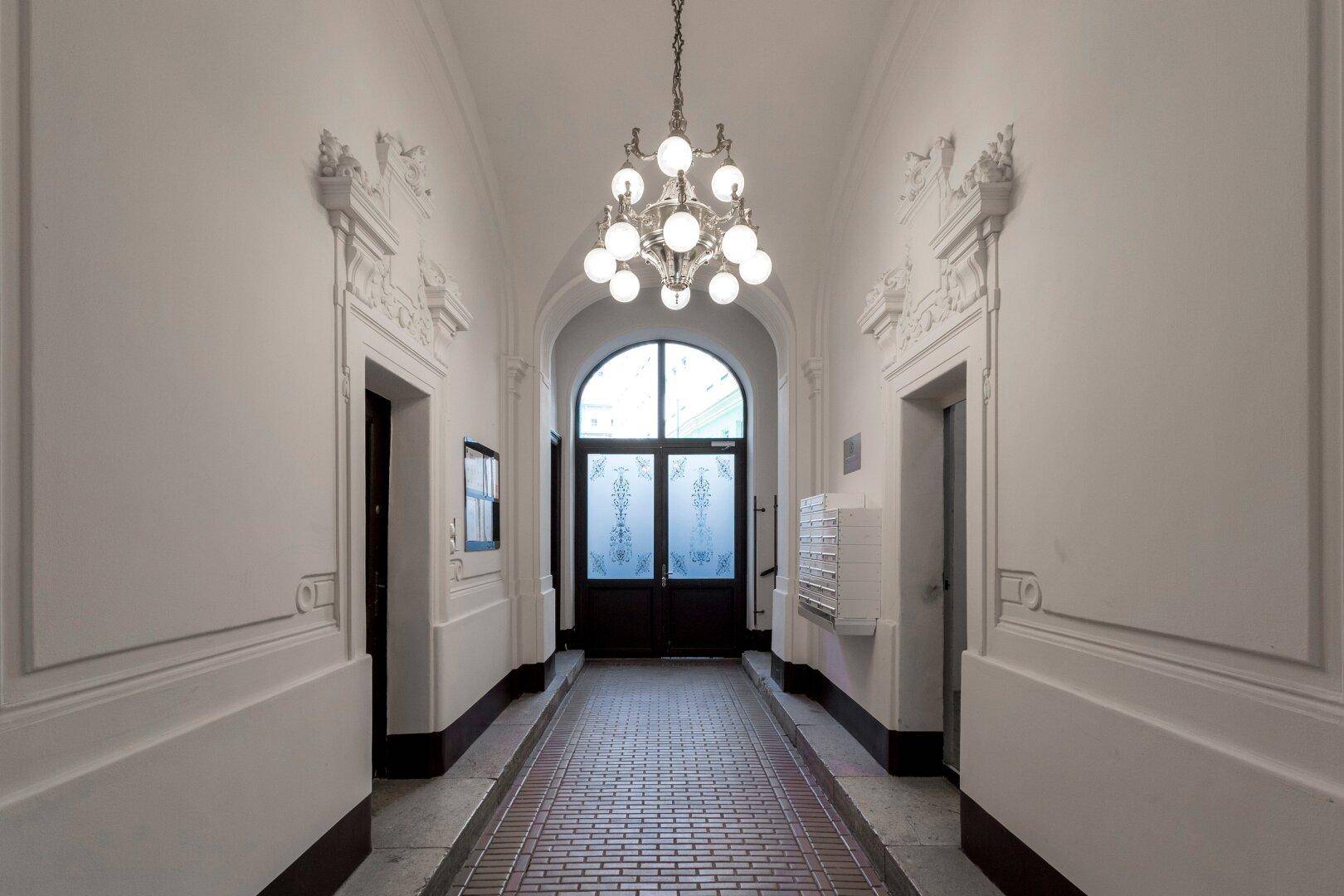 Repräsentativer Flur im Altbau mit Stuckelementen und Kronleuchter.