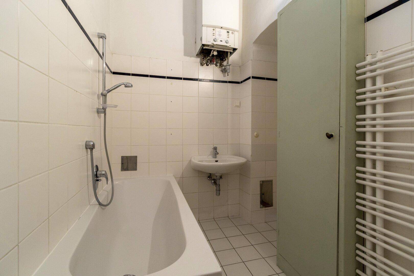 Funktionales Badezimmer mit Badewanne, Waschbecken und Heizkörper, in gutem Zustand.
