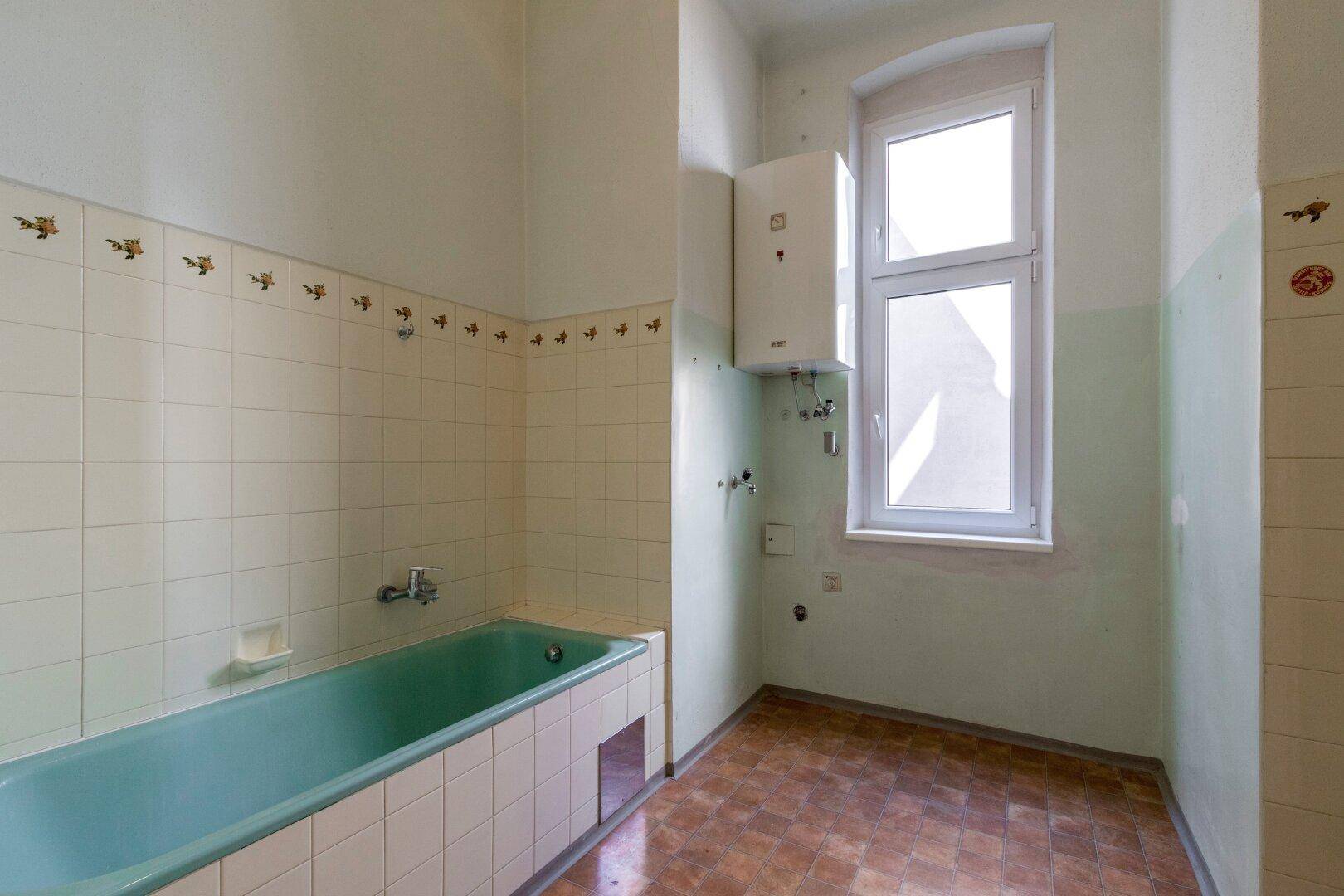 Badezimmer im 80er-Jahre-Stil mit grüner Badewanne und weißen Fliesen, benötigt Renovierung.