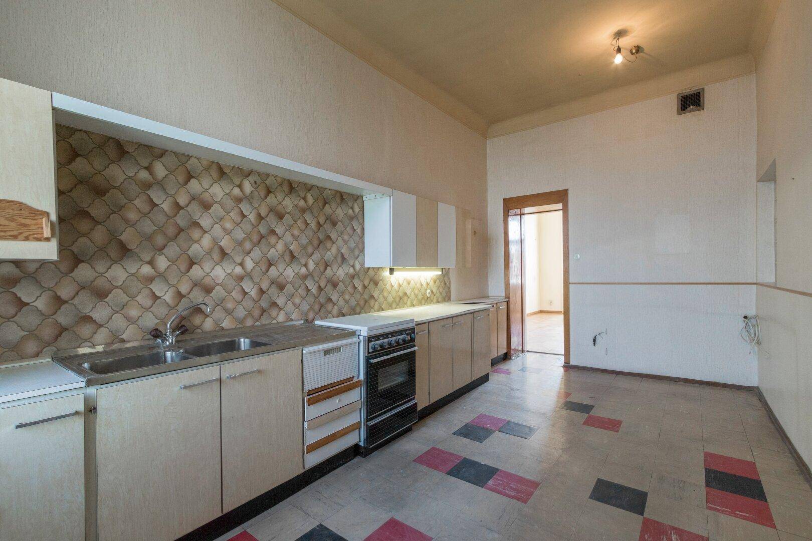 Ältere Küche mit Einbauschränken und farbigem Fliesenboden, bietet Potenzial für eine neue Gestaltung.