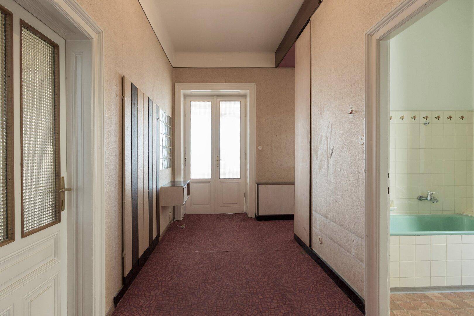 Langer Flur mit Teppichboden und Zugang zu verschiedenen Zimmern, inklusive Badezimmer.