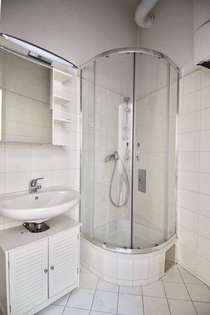 Modernes Badezimmer mit Duschkabine, Waschbecken und weißen Fliesen.