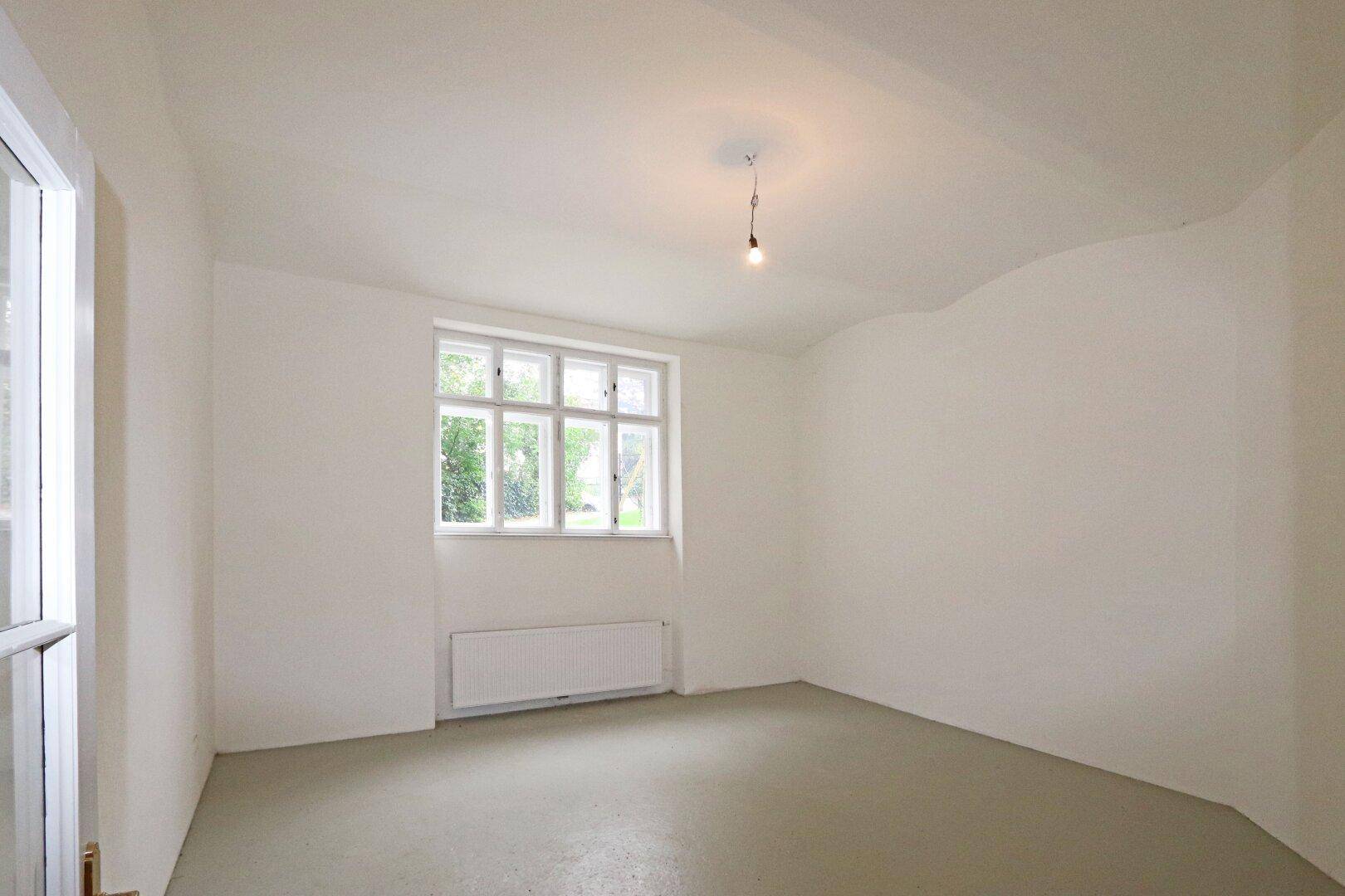 Helles Zimmer mit glattem Boden, großem Fenster und viel Tageslicht.