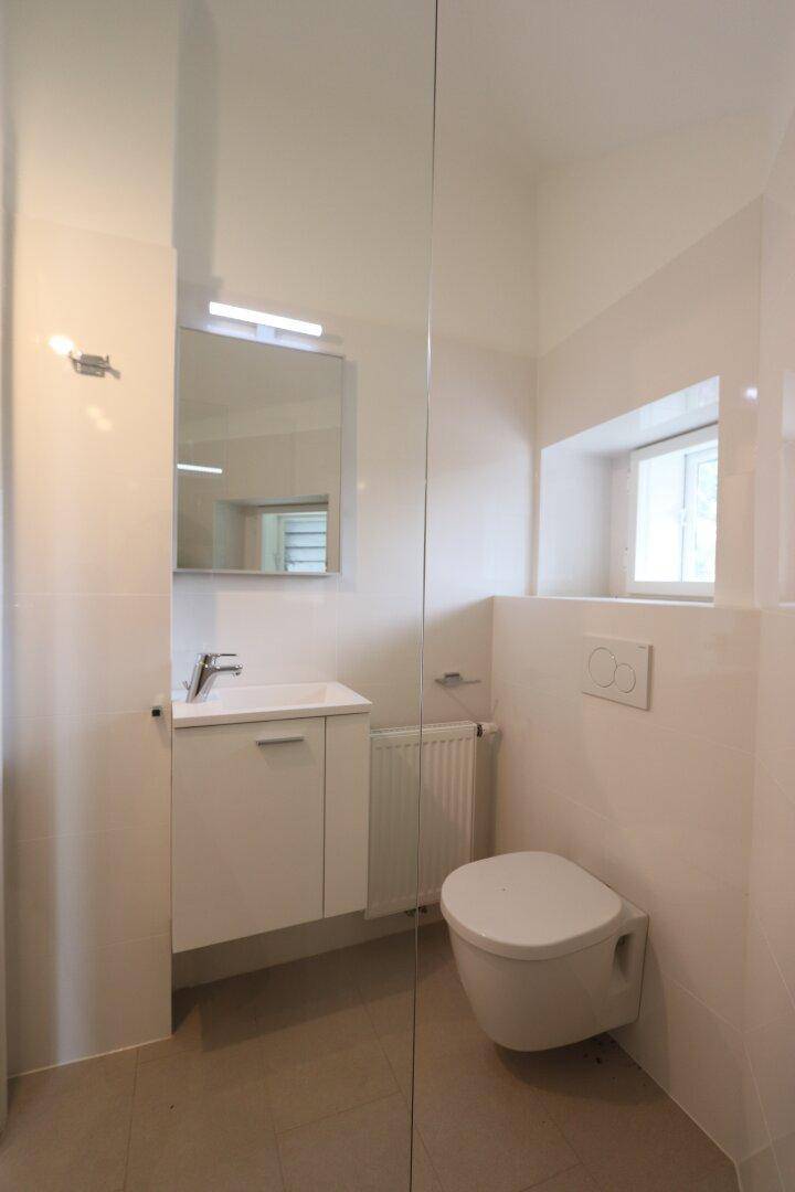 Helles Badezimmer mit modernem Waschtisch, wandhängendem WC und Fenster.