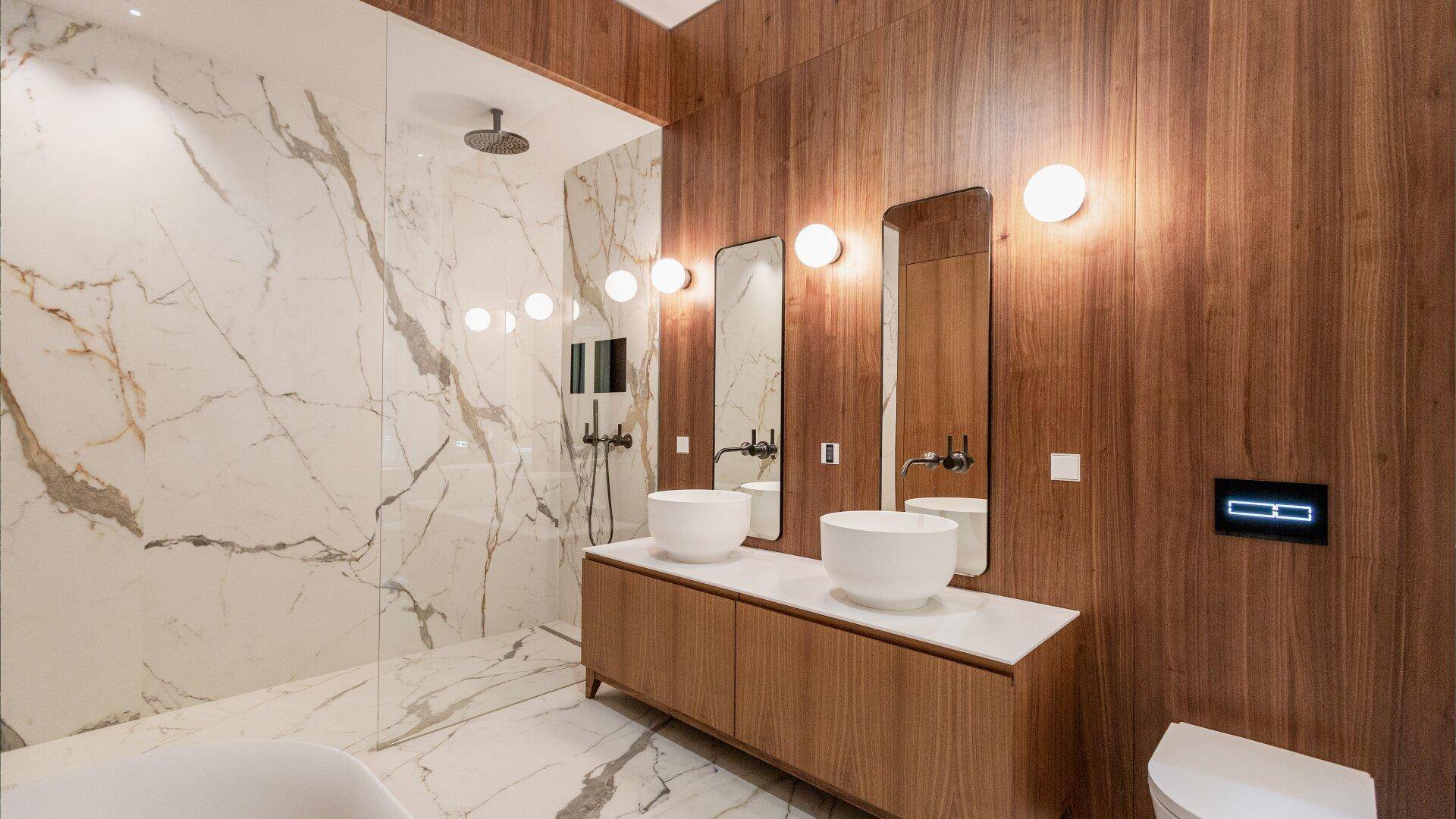 Modernes Badezimmer mit Marmorfliesen, Holzverkleidung, Doppelwaschbecken und Regendusche.