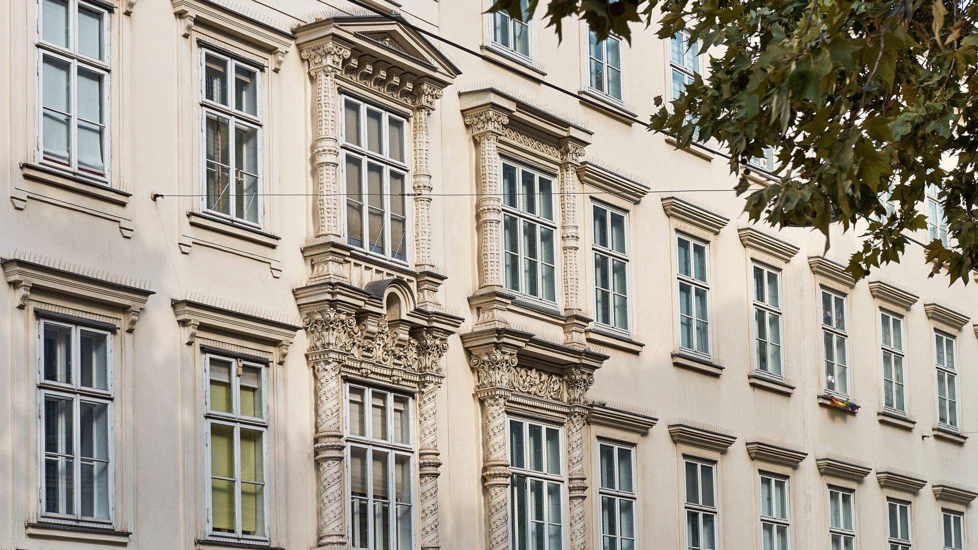 Detailansicht einer historischen Fassade mit reich verzierten Fenstern und Stuckelementen.