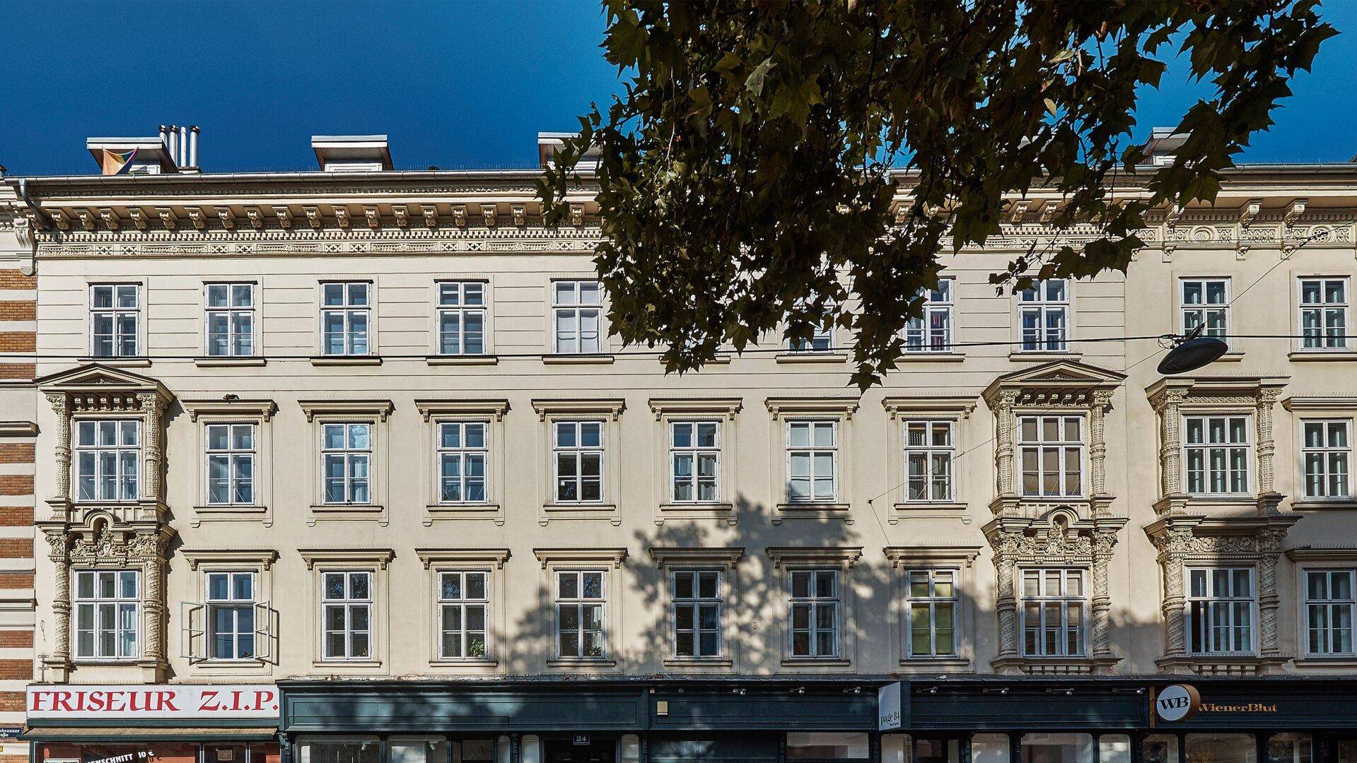 Historische Gebäudefassade mit Geschäften im Erdgeschoss und vielen Fenstern.