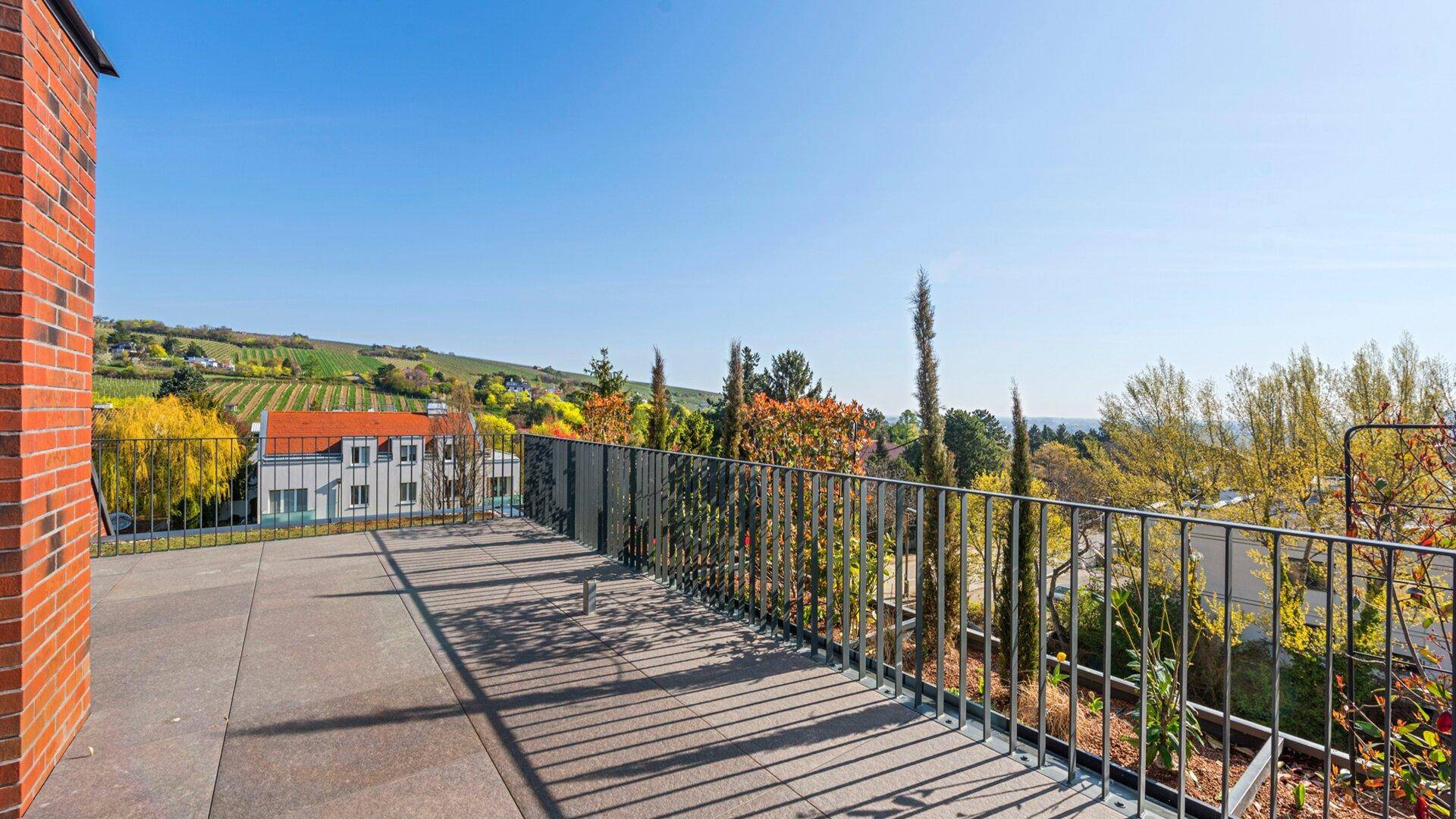 Geräumige Terrasse mit weitem Blick über Weinberge und die umliegende Landschaft unter blauem Himmel.