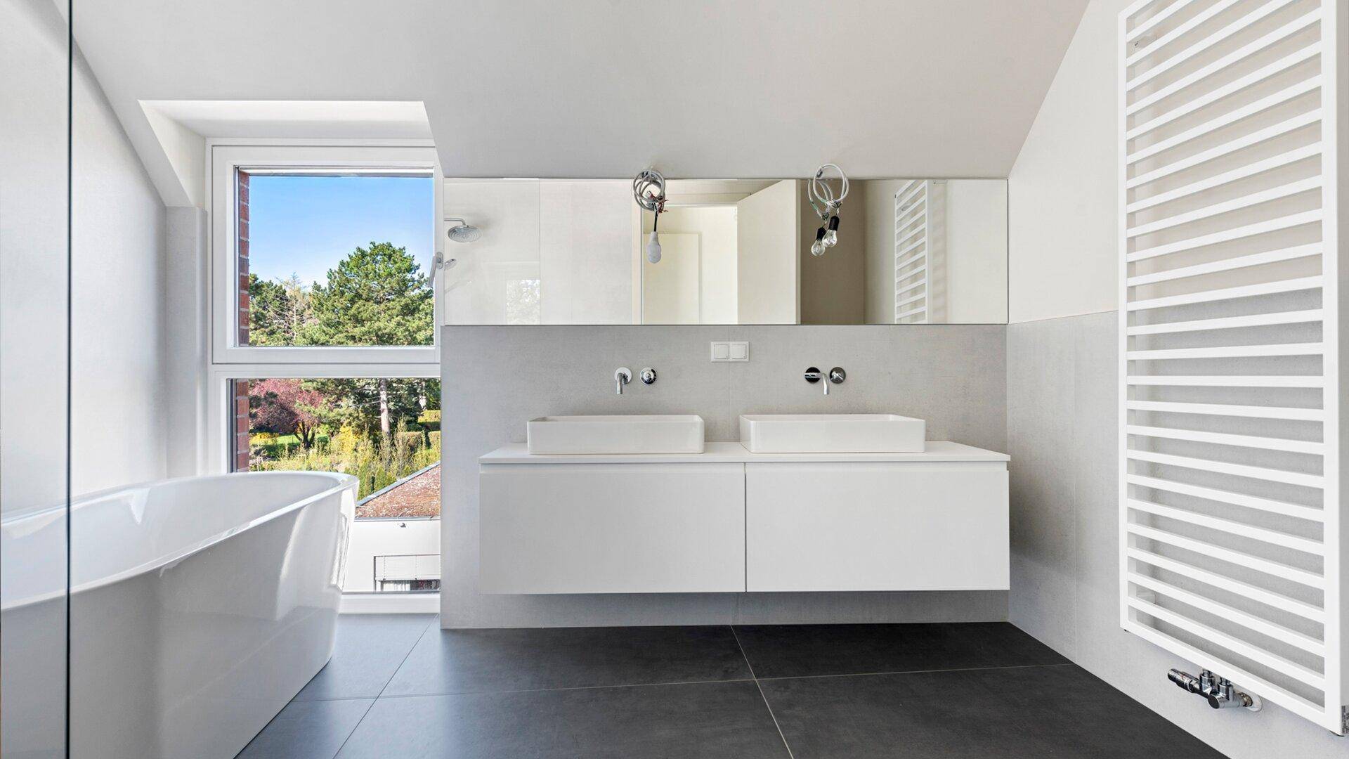 Modernes Badezimmer mit Doppelwaschbecken, freistehender Badewanne und großem Fenster mit Ausblick.