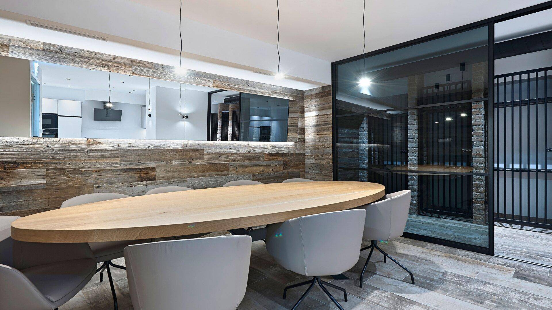 Großer Essbereich mit Holztisch, modernen Stühlen und Holzwandverkleidung.
