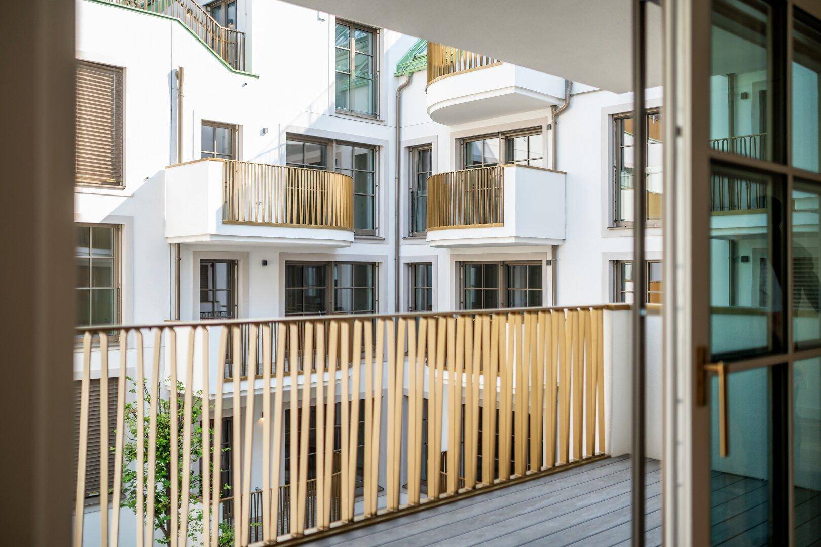 Blick vom Balkon in den begrünten Innenhof des modernen Wohngebäudes.