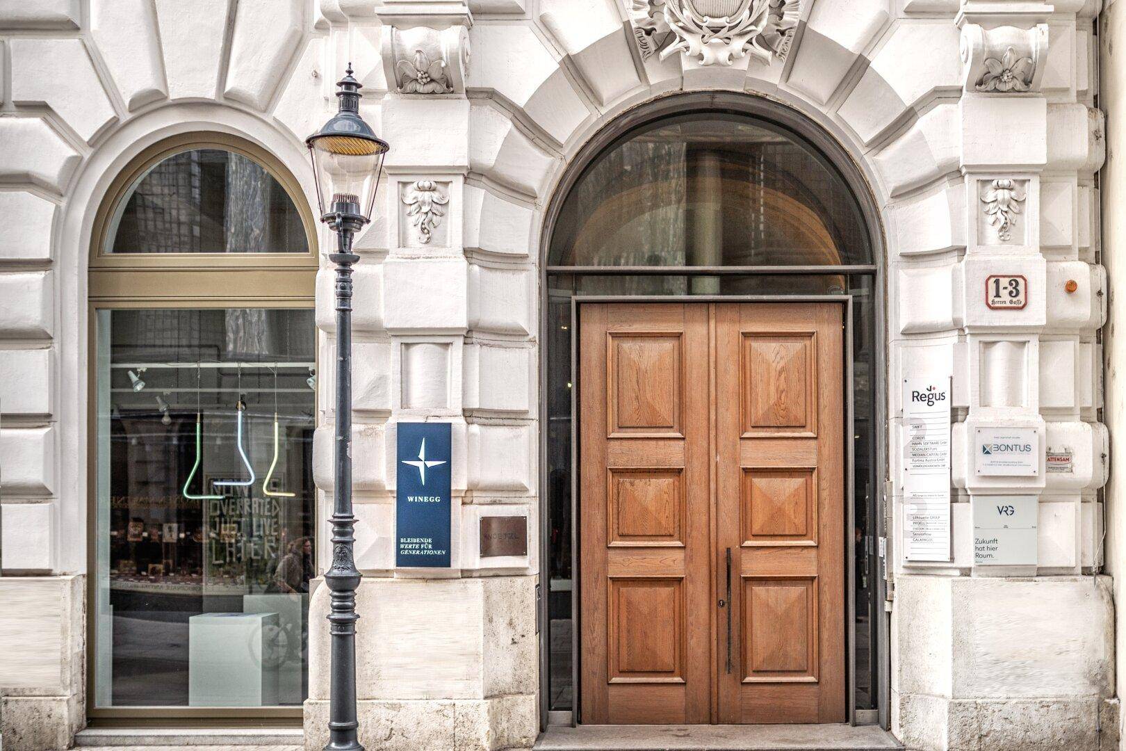 Klassischer Gebäudeeingang mit Holztür, Bogenfenster und historischer Straßenlaterne.