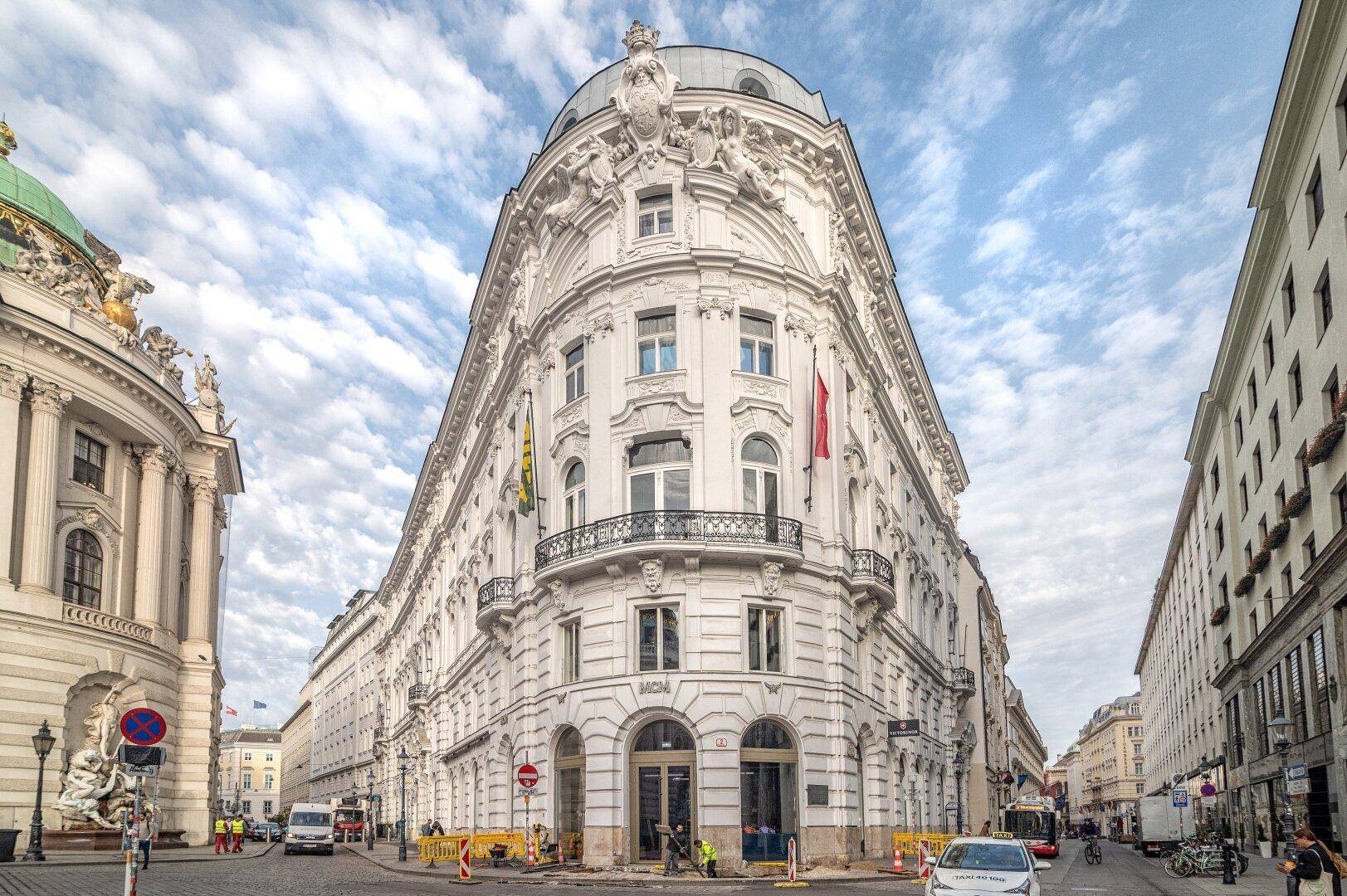 Historisches Eckgebäude mit klassischer Architektur und belebter Straße im Stadtzentrum.