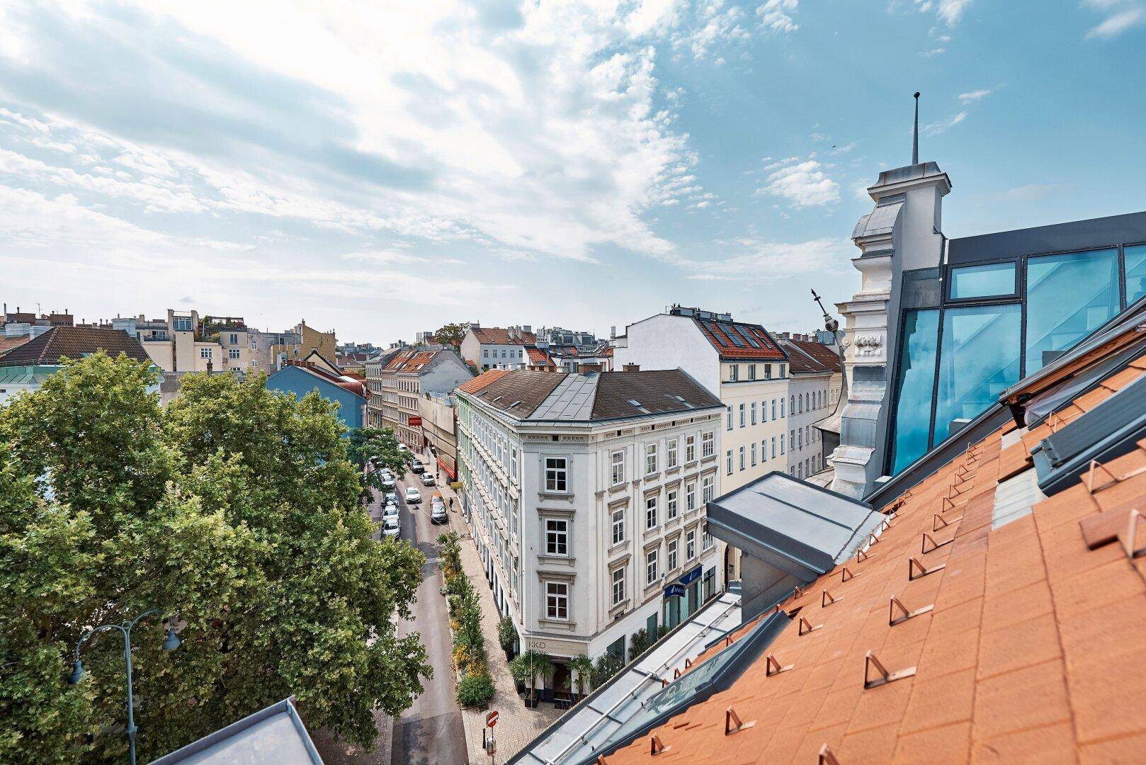 Panoramablick über die Dächer der Stadt mit historischen Gebäuden und grünen Bäumen.