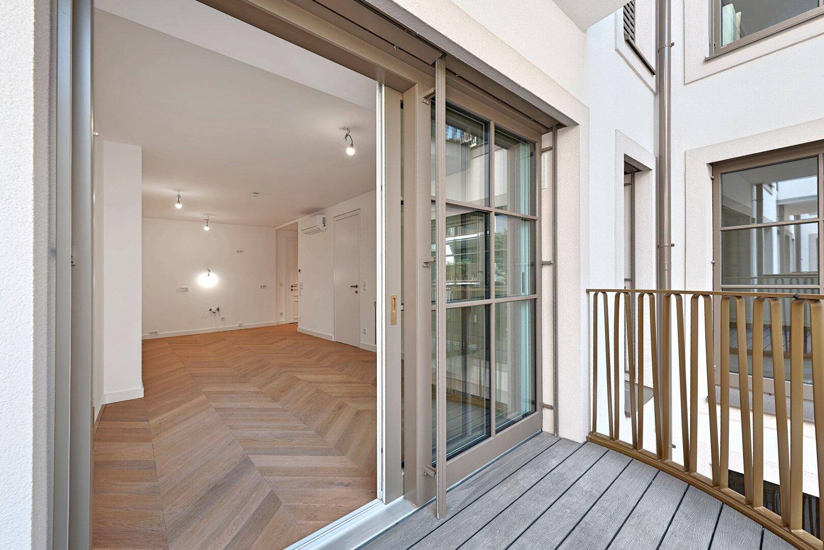 Moderner Balkon mit Holzboden und Blick in den hellen Innenraum.