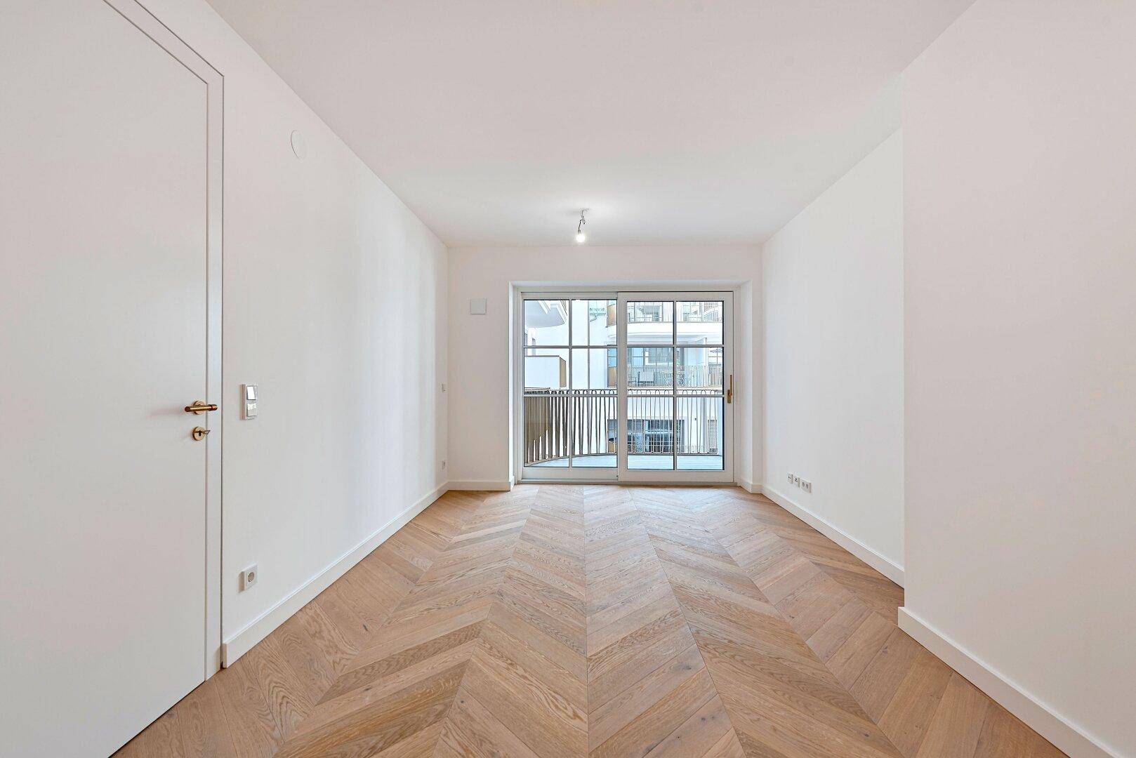 Geräumiges, helles Zimmer mit Fischgrätparkett und großen Schiebetüren zum Balkon.