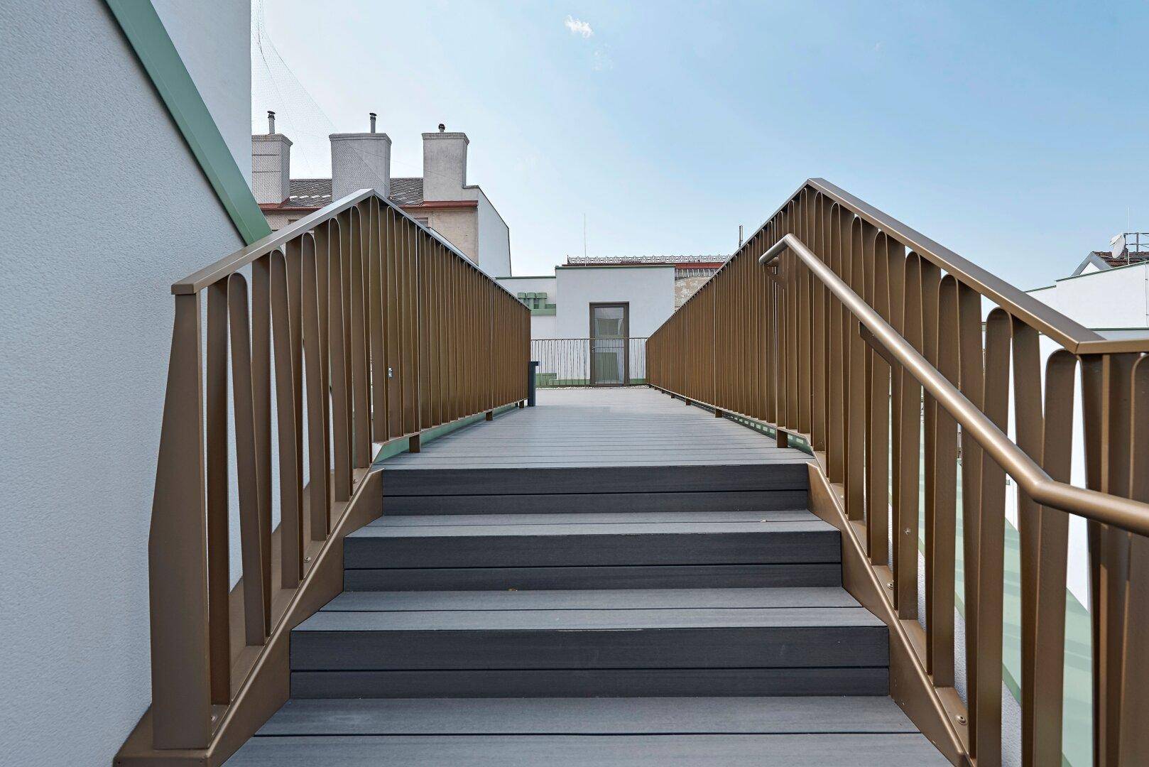 Treppe auf der Dachterrasse mit modernem Geländer und Holzoptik-Stufen.