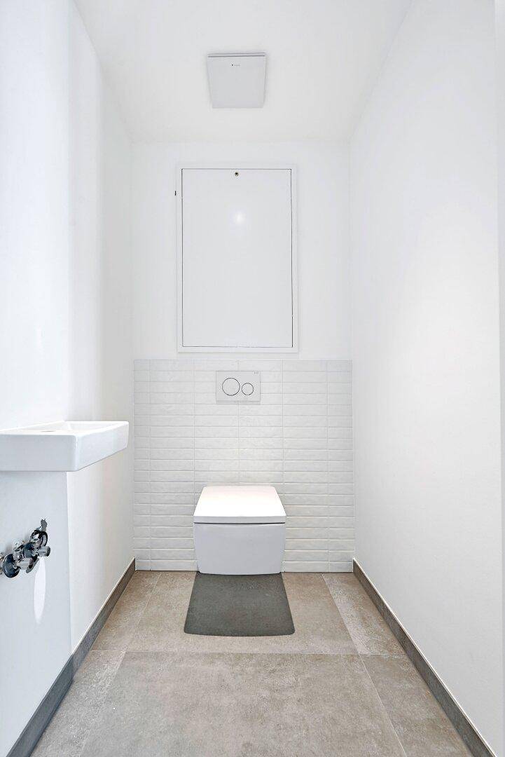 Modernes Gäste-WC mit wandhängender Toilette und kleinem Waschbecken.