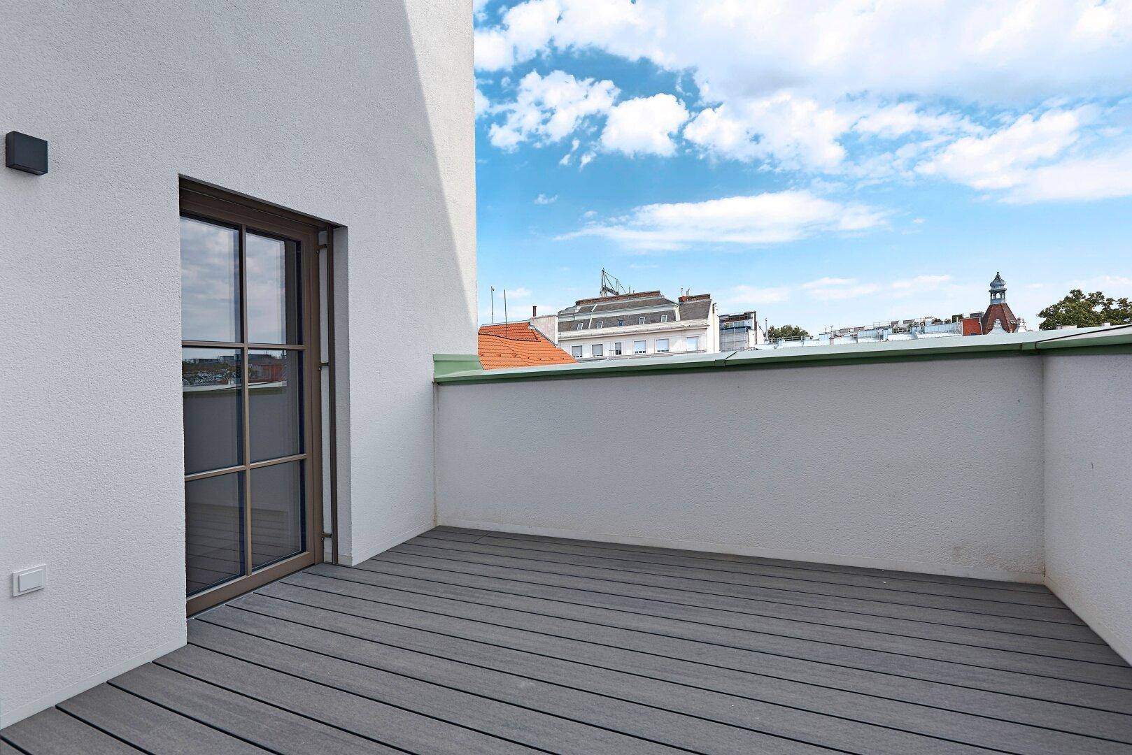Kleine, private Terrasse mit Holzdielenboden und Blick auf die umliegenden Dächer.