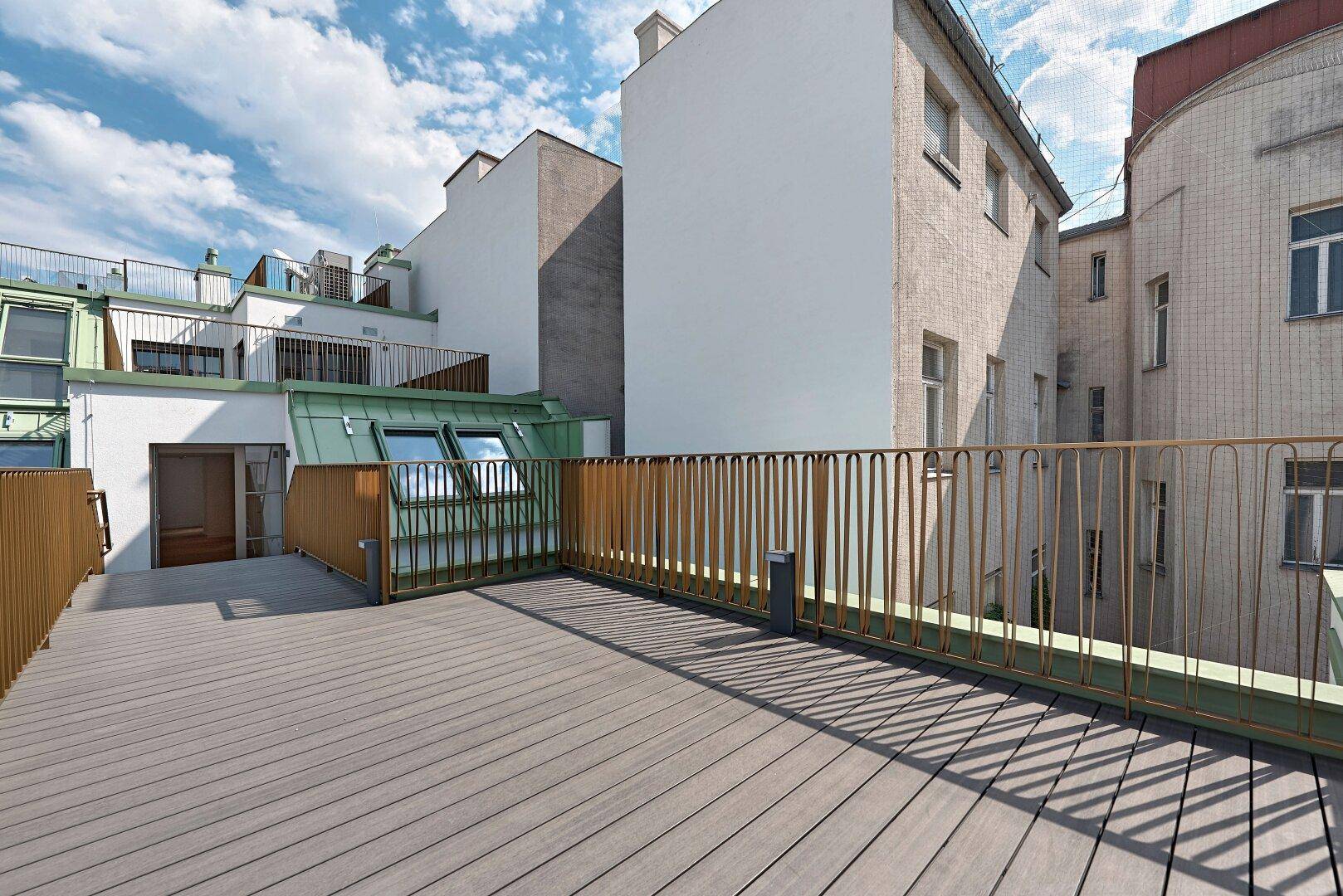 Weitläufige Dachterrasse mit modernem Geländer und Blick auf die umliegenden Gebäude.