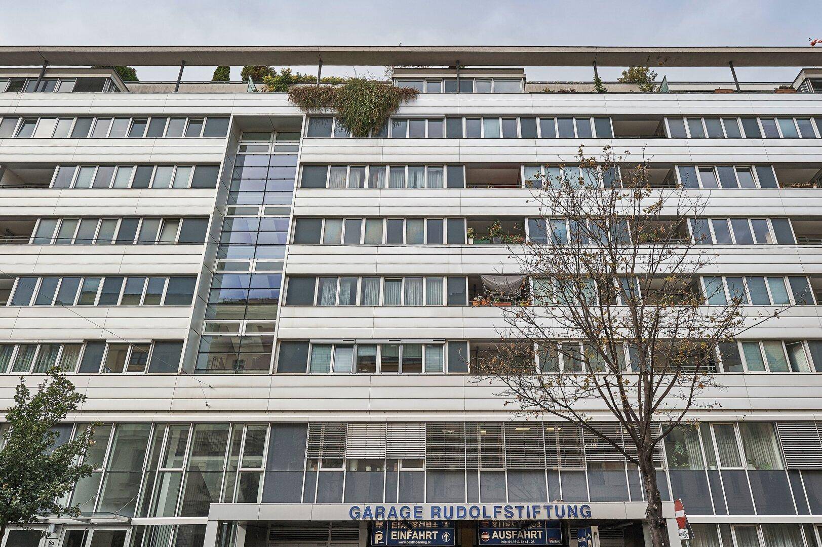 Nahaufnahme der modernen Gebäudefassade mit vielen Fenstern und der Einfahrt zur Tiefgarage.