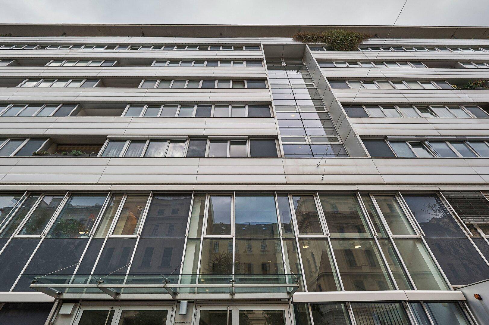 Detailansicht der modernen Gebäudefassade mit Glasfront und zahlreichen Fenstern.