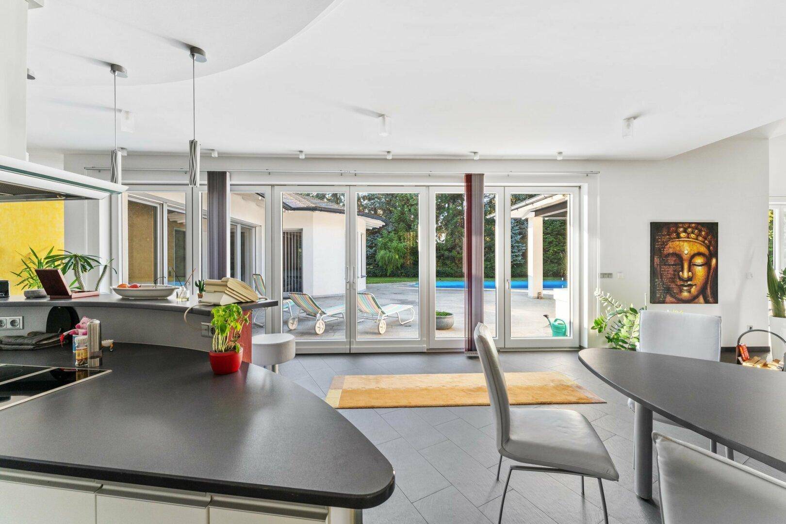 Offener Essbereich mit großzügigen Fensterfronten und direktem Zugang zum Poolbereich und Terrasse.