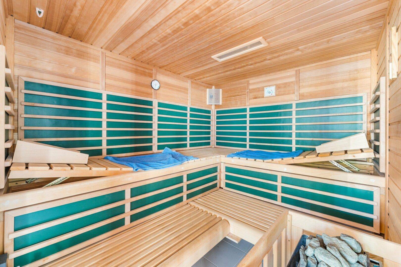 Geräumige Holzsauna mit mehreren Bänken und integriertem Heizofen für Entspannung.
