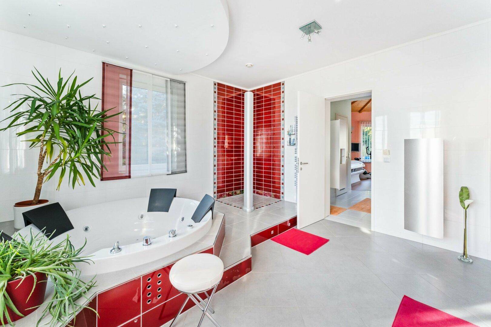 Luxuriöses Badezimmer mit Whirlpool, Dusche und roten Akzentfliesen für ein Spa-Erlebnis.