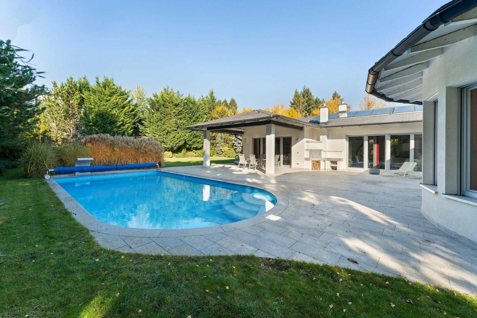 Großzügige Poolterrasse mit Liegeflächen und Blick auf den gepflegten Garten.
