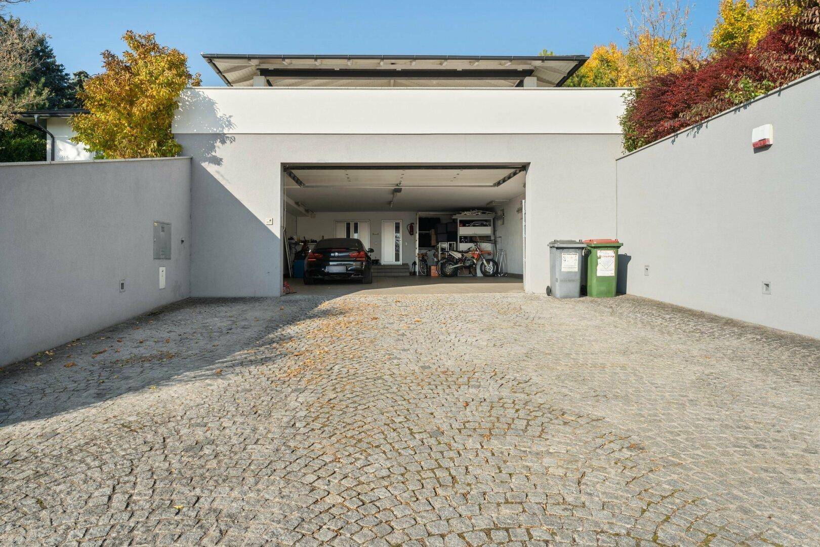 Einfahrt zur Tiefgarage mit gepflastertem Vorplatz und moderner Fassade.