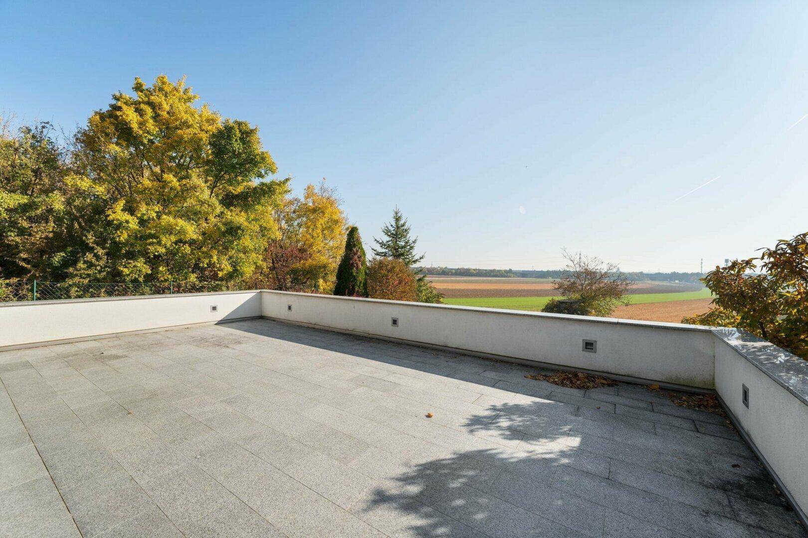 Große, sonnige Terrasse mit Fliesenboden und weitem Blick über die Landschaft.