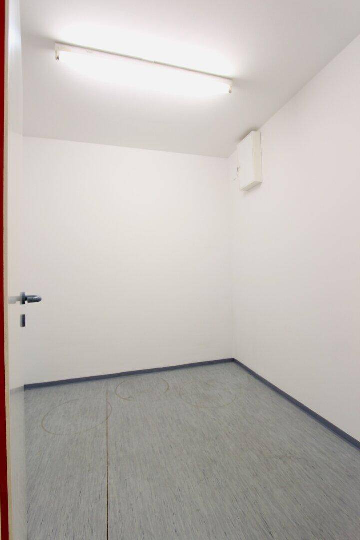 Kleiner, leerer Raum mit grauem Boden und weiß gestrichenen Wänden, ideal als Abstellraum.