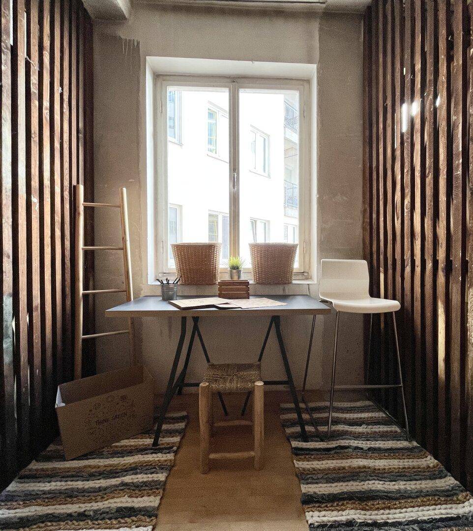 Kreativer Arbeitsbereich mit Holzwänden, Schreibtisch, Stühlen und Fensterblick.