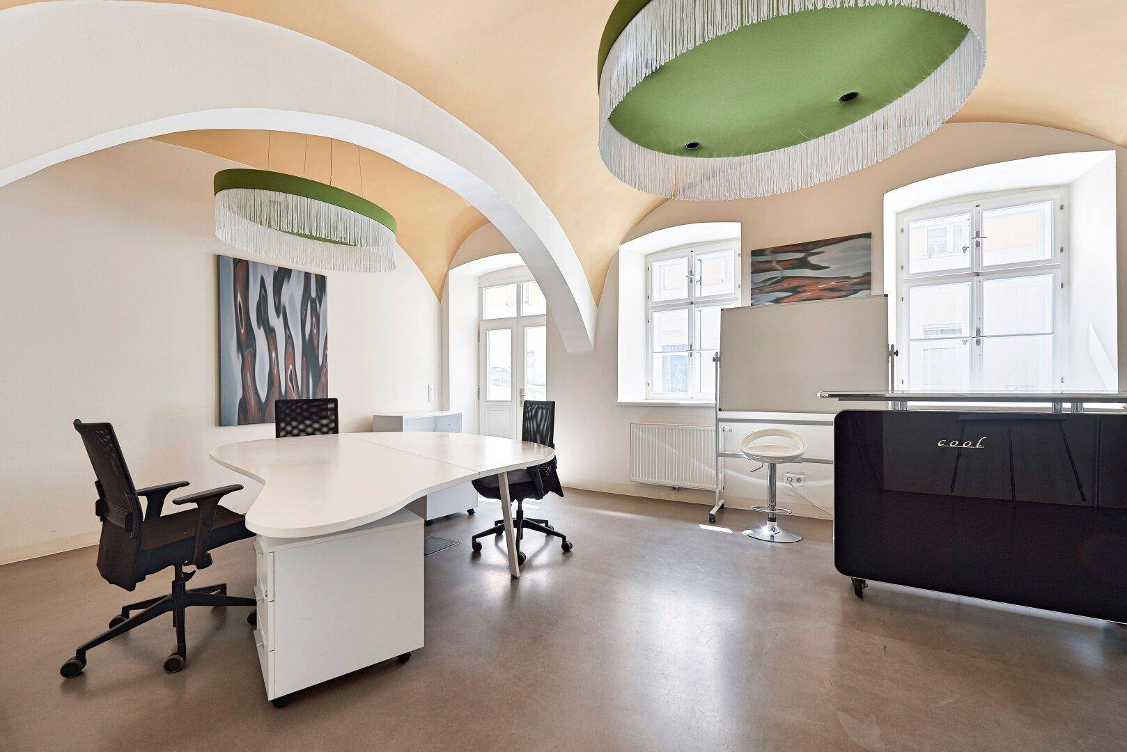 Büro mit beeindruckender Gewölbedecke, modernen Arbeitsplätzen und großen Fenstern für viel Tageslicht.