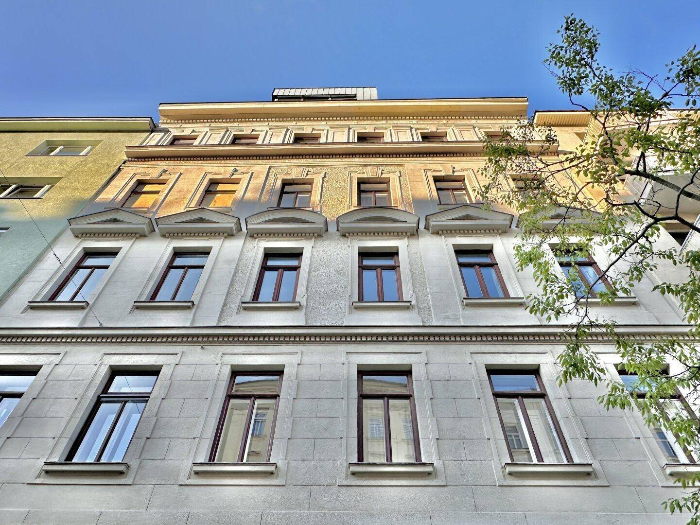 Detailansicht der historischen Fassade mit verzierten Fenstern und klassischer Architektur unter blauem Himmel.