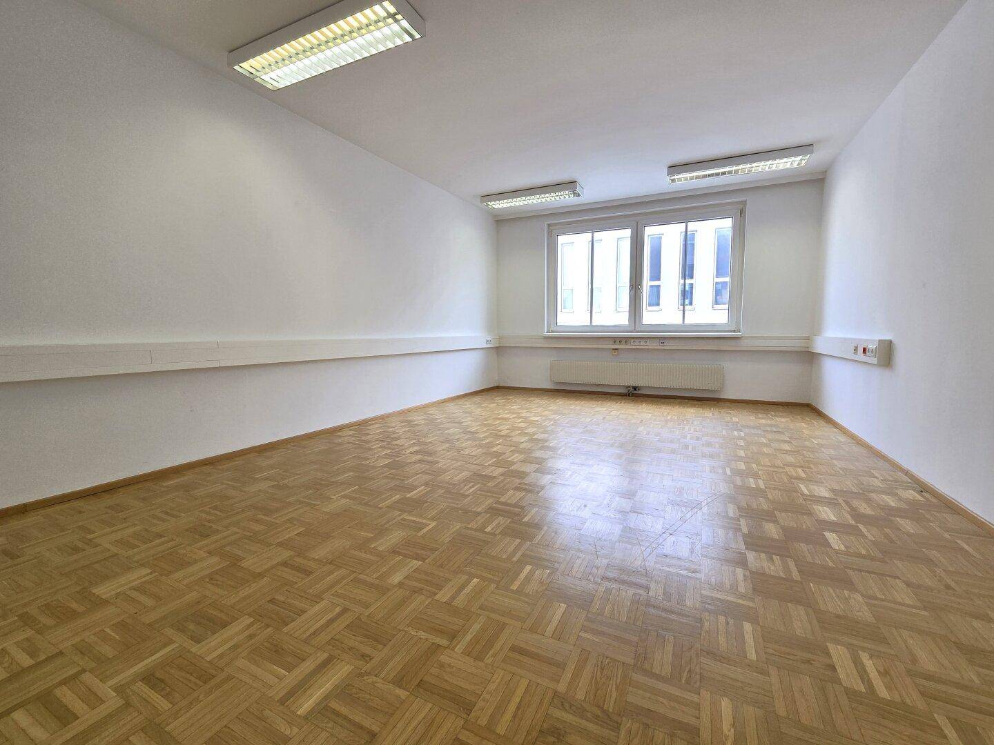 Helles Büro mit Parkettboden und großen Fenstern, das eine freundliche und produktive Umgebung bietet.