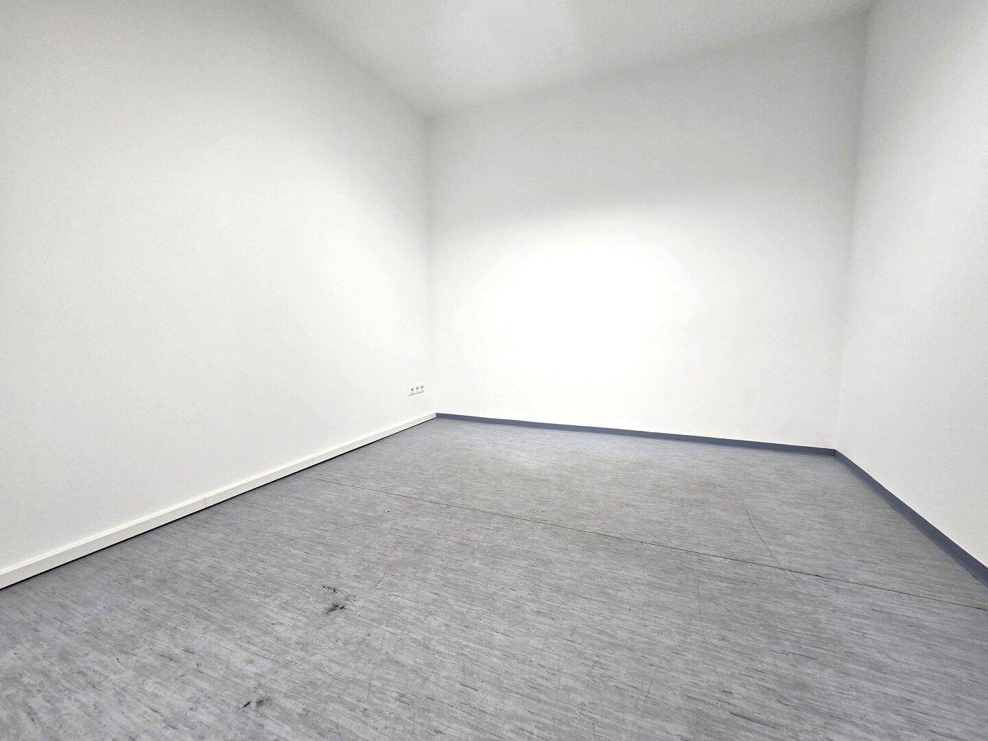 Leerer Raum mit grauem Betonboden und weißen Wänden, ideal als Lager- oder Abstellraum.